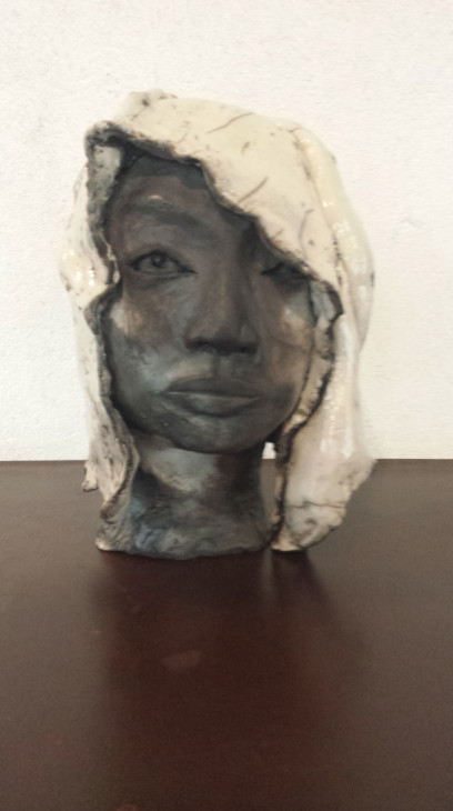 photo de sculpture raku, une tête de jeune femme, son voile émaillé blanc lui couvre la moitié du visage noir mat